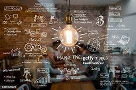 A light bulb illuminating a glass board covered with handwritten marketing strategies, icons, and diagrams.