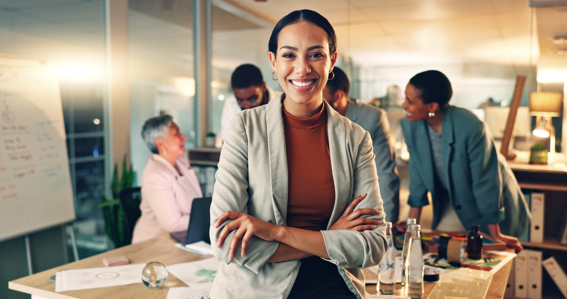 Face, business and woman with arms crossed, smile and career with teamwork, meeting or planning. Portrait, person or employee with cooperation, staff or professional with brainstorming in a workplace